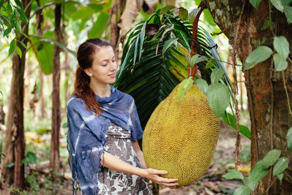 young-female-tourist-in-asia-holding-jackfruit-in-2023-11-27-05-20-48-utc